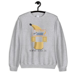May include: Gray sweatshirt with a graphic of a banana-shaped frozen banana stand with the text "Doug's Original Frozen Banana" and "Newport Beach, CA."