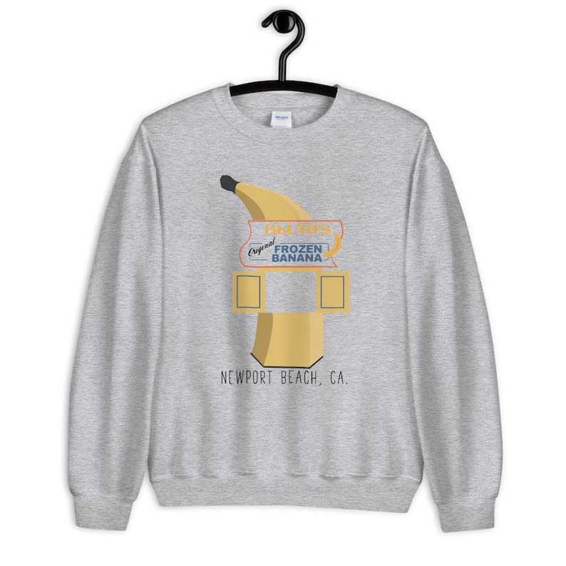 May include: Gray sweatshirt with a graphic of a banana-shaped frozen banana stand with the text "Doug's Original Frozen Banana" and "Newport Beach, CA."