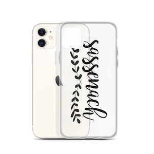 Może przedstawiać: Przezroczyste etui na telefon z czarnym wzorem kwiatowym i napisem "Sassenach" napisanym kursywą.