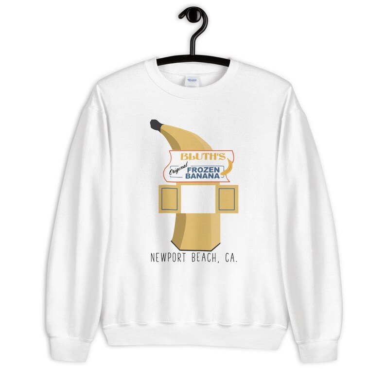 May include: White sweatshirt with a graphic of a banana and a sign that reads "Bluth's Original Frozen Banana - Newport Beach, CA."