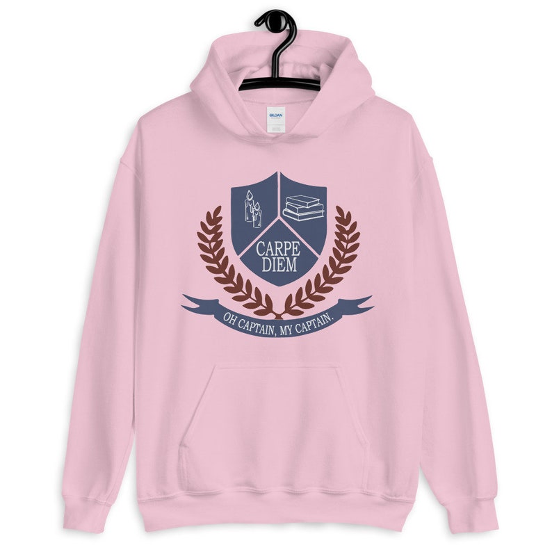 May include: Pink hoodie with a blue and brown crest featuring a book stack, candles, and the text "Carpe Diem" and "Oh Captain, My Captain".