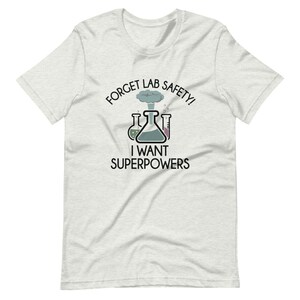 May include: A white t-shirt with a black graphic of beakers and an exploding flask. The text reads "Forget Lab Safety! I Want Superpowers".