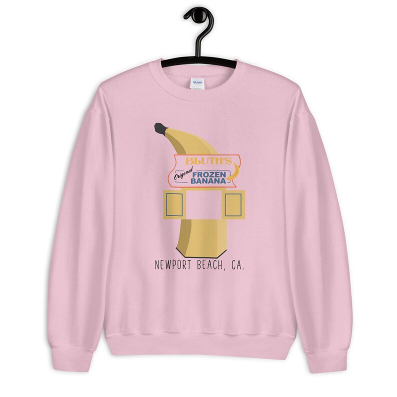 May include: Pink sweatshirt with a graphic of a banana stand with the text "Bluth's Original Frozen Banana" and "Newport Beach, CA."
