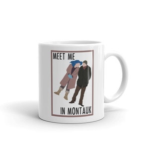 Könnte beinhalten: Weiße Keramiktasse mit einem braunen Rechteck, das eine Schwarzweißillustration eines Paares zeigt, das spazieren geht. Der Text "Meet Me In Montauk" ist in schwarzer Schrift unter der Illustration gedruckt.