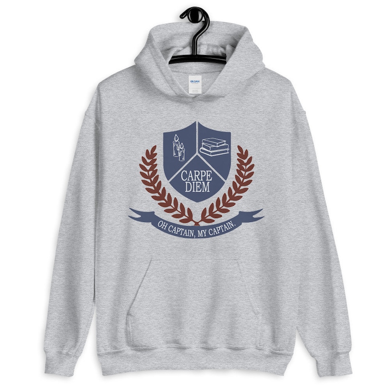 May include: A gray hooded sweatshirt with a blue crest featuring a book stack, candles, and the text "Carpe Diem". A laurel wreath surrounds the crest, and the text "Oh Captain, My Captain" is below the crest.