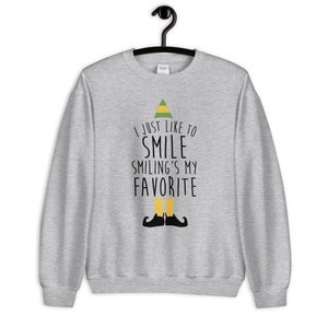 May include: A grey sweatshirt with a green elf hat and the text "I just like to smile smiling's my favourite".