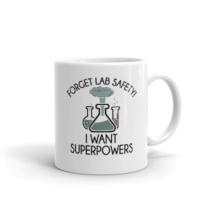 May include: White ceramic coffee mug with a black graphic of beakers and an exploding flask. The text reads "Forget Lab Safety! I Want Superpowers".