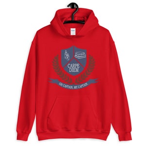 May include: Red hooded sweatshirt with a blue crest featuring a stack of books, candles, and the text "Carpe Diem". The crest is surrounded by a laurel wreath and the text "Oh Captain, My Captain".