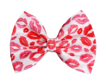 May include: A white bow tie with a red lip print pattern.