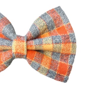Plaid bow tie has a small check design. Stripes of orange and yellow lay on a light blue gray.