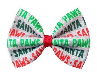 May include: A gray bow with a red center, featuring a repeating pattern of the words "Santa Paws" in green and red lettering.