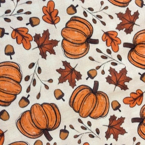 The bandana features orange pumpkins and leaves and is paired with an orange gingham backing.