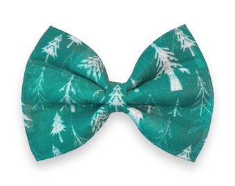 May include: A teal blue bow tie with a white Christmas tree pattern.