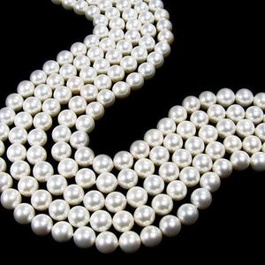 May include: Strands of lustrous, creamy white pearls against a black background. The pearls are round and evenly sized, creating a smooth, elegant texture. The image showcases the pearls' natural sheen and classic appeal.