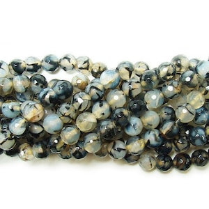 May include: Strand of faceted gemstone beads. The beads are primarily gray, black, and cream-colored, with a marbled appearance. The beads are round and have a polished, reflective surface. Ideal for jewelry making.