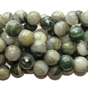 May include: A strand of faceted, round beads in shades of green, white, and gray. The beads have a polished, gemstone appearance and are strung together. The beads are approximately 10mm in diameter.