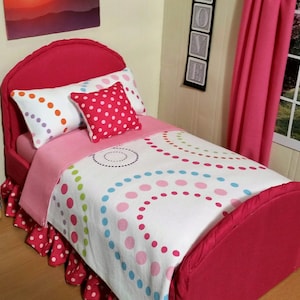May include: A pink and white twin-sized bed with a white polka dot and swirl patterned comforter. The bed has a pink headboard and a pink ruffled bed skirt.