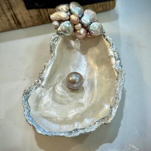 Un pezzo unico di conchiglia di ostrica della costa del Golfo raccolta a mano, ricoperta di una grande perla d'acqua dolce color argento iridescente e lavanda.