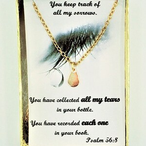 May include: A gold-colored necklace with a teardrop pendant, displayed on a card with inspirational text. The card has a gold border and features the quote "You keep track of all my sorrows." and "Psalm 56:8".