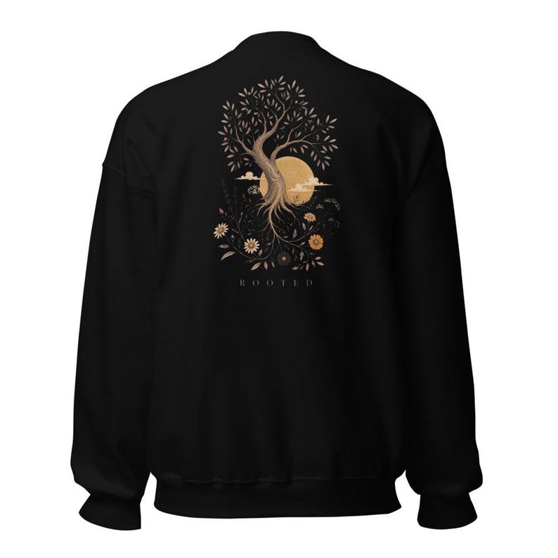 May include: A black crewneck sweatshirt featuring a graphic on the back. The design displays a tree with exposed roots, a large circular moon, and various flowers in shades of beige and brown. The word ROOTED is printed below the illustration.
