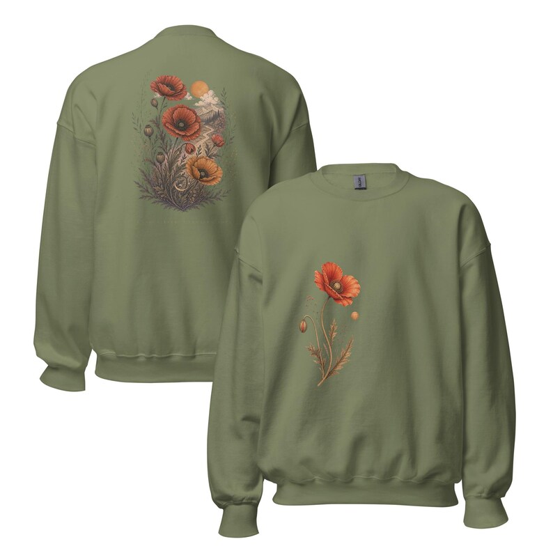 May include: An olive green crewneck sweatshirt featuring a single red poppy flower graphic on the front chest. The back of the sweatshirt displays a larger, detailed illustration of multiple red poppies, foliage, and a sun in a landscape setting.