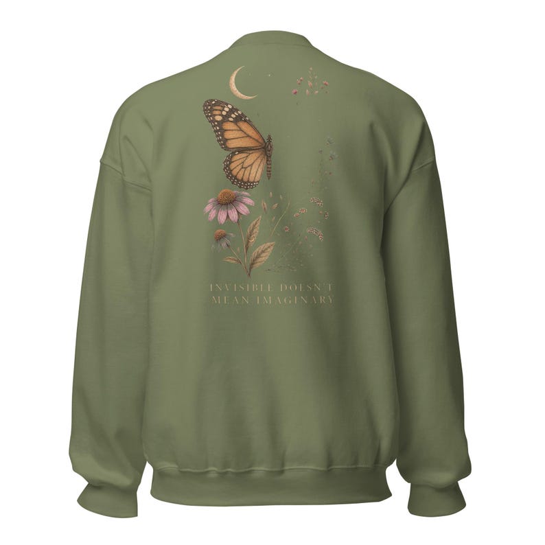 May include: An olive green crewneck sweatshirt featuring a back graphic of a monarch butterfly, a pink coneflower, and a crescent moon. The text "INVISIBLE DOESN'T MEAN IMAGINARY" is printed in a light color below the floral and insect illustration.