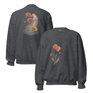 May include: A dark heather gray crewneck sweatshirt featuring a single orange poppy flower graphic on the front. The back of the sweatshirt displays a larger, detailed illustration of multiple orange poppies, foliage, and a sun-like circular element.