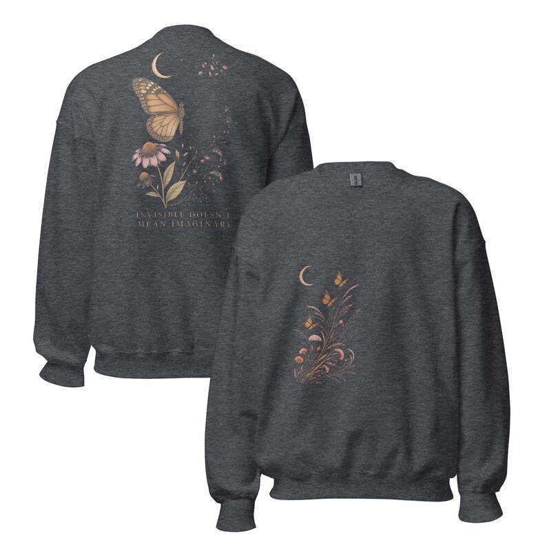 May include: A dark heather gray crewneck sweatshirt featuring a butterfly, flowers, and a crescent moon graphic on the front and back. The back design includes the text "INVISIBLE DOESN'T MEAN IMAGINARY" printed in a light, neutral tone.