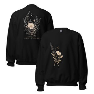 May include: A black crewneck sweatshirt featuring a floral and crescent moon graphic on the front and a larger version of the same design on the back with the text FIBROMYALGIA SOFTLY UNBROKEN printed in white capital letters below the floral arrangement.