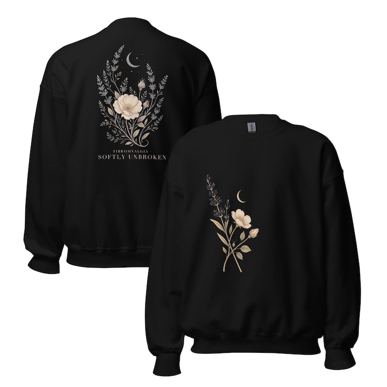 May include: A black crewneck sweatshirt featuring a floral and crescent moon graphic on the front and a larger version of the same design on the back with the text FIBROMYALGIA SOFTLY UNBROKEN printed in white capital letters below the floral arrangement.