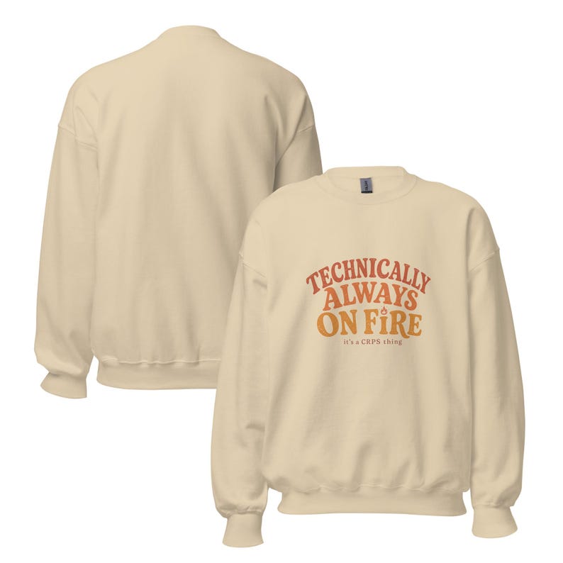 May include: A cream-colored crewneck sweatshirt featuring the text "TECHNICALLY ALWAYS ON FIRE" in a curved, orange-to-yellow gradient font, with a small flame icon above the word "FIRE" and the smaller text "it's a CRPS thing" below.