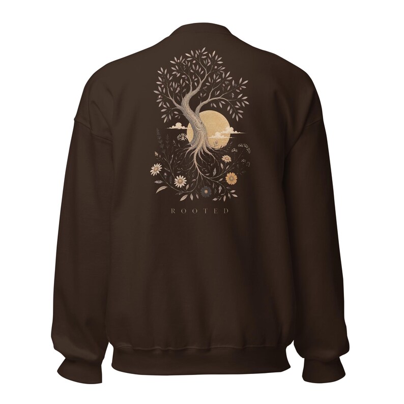 May include: A dark brown crewneck sweatshirt featuring a graphic on the back of a tree with exposed roots, surrounded by various flowers and a large circular moon. The word ROOTED is printed in capital letters below the tree illustration.