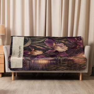 May include: A rectangular throw blanket featuring a dark, atmospheric scene of purple and cream iris flowers near a reflective body of water. A butterfly is visible on the left side, along with a vertical cream-colored banner reading Lupus - Living Beautifully.