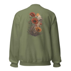 May include: An olive green crewneck sweatshirt featuring a back graphic of red and orange poppy flowers, green foliage, a winding path, distant mountains, and a sun in the sky. The design is centered on the back of the long-sleeved pullover garment.