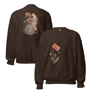 May include: A dark brown crewneck sweatshirt featuring a floral graphic. The front displays a single orange poppy flower with stems and leaves. The back shows a larger, detailed illustration of multiple poppies, foliage, and a sun.