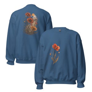 May include: A blue crewneck sweatshirt featuring a large graphic on the back of red and orange poppy flowers with a sun and clouds, and a smaller matching poppy graphic on the front left chest. The long-sleeved garment has a ribbed collar and cuffs.