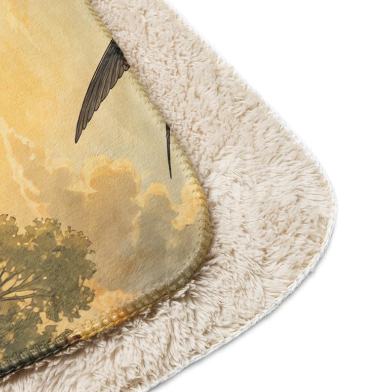 May include: A rectangular throw blanket featuring a printed scene of a bird in flight against a golden yellow sky with clouds and green trees. The reverse side of the blanket is made of a thick, cream-colored, textured sherpa fleece material.
