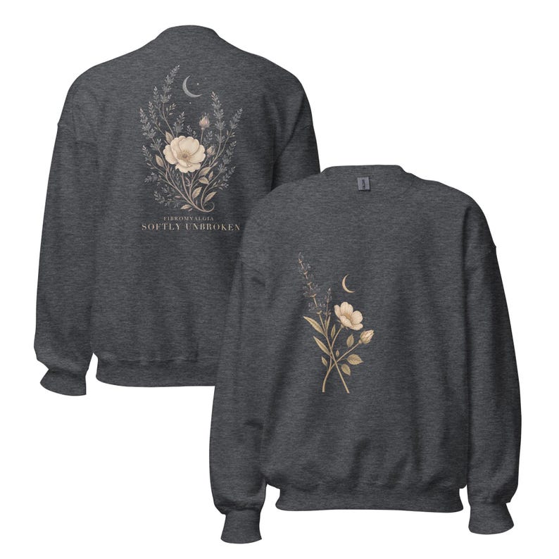 May include: A dark charcoal gray crewneck sweatshirt featuring a botanical illustration of flowers and a crescent moon. The back displays the text "FIBROMYALGIA SOFTLY UNBROKEN" below the floral design, while the front shows a smaller floral graphic.