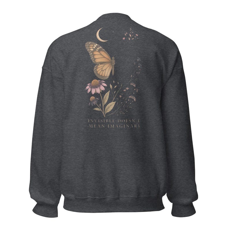 May include: A dark charcoal gray crewneck sweatshirt featuring a back graphic of a monarch butterfly, a crescent moon, and purple coneflower blossoms. The text "INVISIBLE DOESN'T MEAN IMAGINARY" is printed in a light, serif font below the floral design.