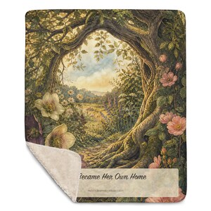 May include: A rectangular throw blanket with a sherpa fleece backing and a printed front featuring a forest scene with a large tree archway, pink roses, white flowers, and a meadow. The text reads "Became Her Own Home" and "NEXT CHAPTER COLLECTION".
