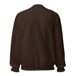 May include: A solid dark brown long-sleeve sweatshirt featuring a crew neckline, ribbed cuffs at the wrists, and a ribbed hem at the bottom. The garment is displayed from the back, showing a plain, unpatterned fabric surface throughout the entire piece.