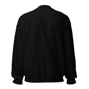 May include: A solid black long-sleeve crewneck sweatshirt shown from the back. The garment features a ribbed collar, ribbed cuffs at the end of the sleeves, and a ribbed hem at the bottom. The fabric is a uniform, deep black color throughout.