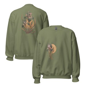 May include: An olive green crewneck sweatshirt featuring a botanical illustration of an iris flower in front of a golden circular moon. The back of the sweatshirt displays a larger version of the same iris and moon graphic with text below.