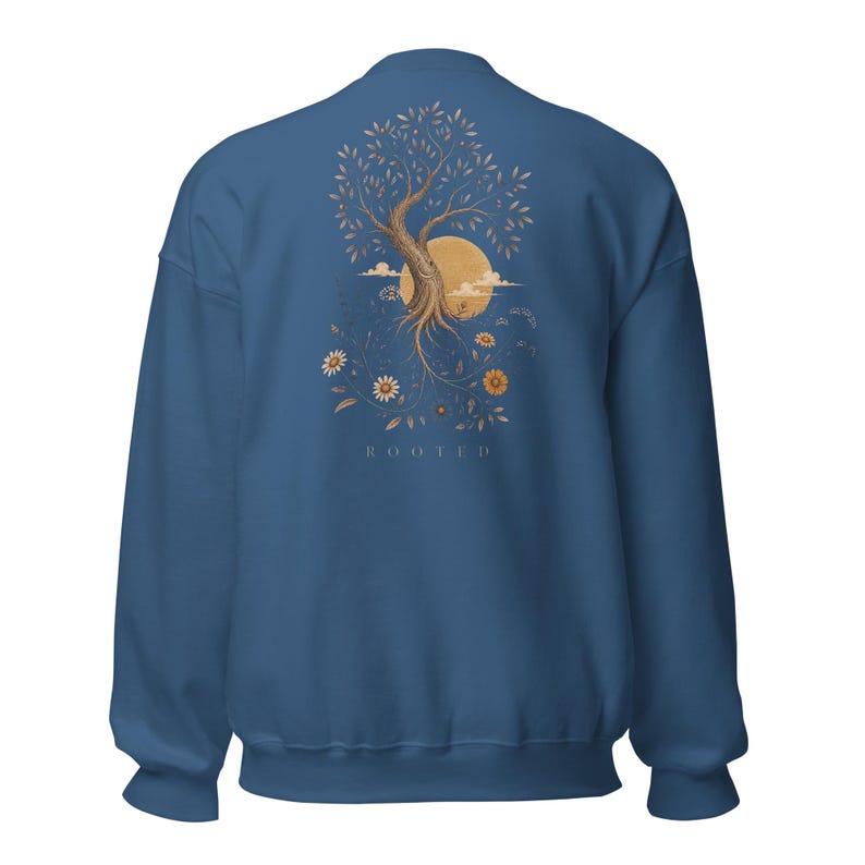 May include: A blue crewneck sweatshirt featuring a graphic on the back of a tree with exposed roots, a large golden sun, and various flowers. The word ROOTED is printed in small, capitalized letters beneath the tree illustration.
