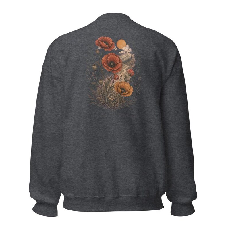 May include: A charcoal gray long-sleeve sweatshirt featuring a graphic on the back. The design displays red and orange poppy flowers, foliage, and a small sun set against a landscape with a winding path, rendered in muted, earthy tones.