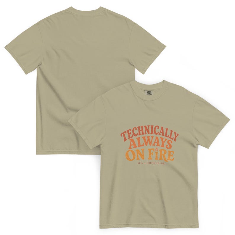 Puede incluir: Una camiseta de manga corta en color verde oliva claro con el texto en naranja y rojo "TECHNICALLY ALWAYS ON FIRE" y el texto m&aacute;s peque&ntilde;o "it's a CRPS thing" debajo. La parte trasera de la camiseta es lisa y de color verde oliva claro.