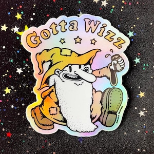 May include: A holographic sticker featuring a cartoon wizard with a long white beard, wearing a yellow hat and holding a can of beer. The sticker says "Gotta Wizz" in a rainbow font.