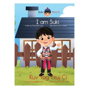 May include: A children's book cover with a cartoon illustration of a boy wearing a red and black patterned shirt and pants. The book title is "I am Suki" and the subtitle is "Kuv Yog Txuj Ci".