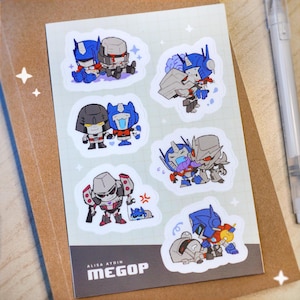 May include: A sticker sheet with cartoon Transformers illustrations. The stickers show pairs of characters in various poses and expressions. The sheet has a grid background and the text "ALISA AYDIN MEGOP".