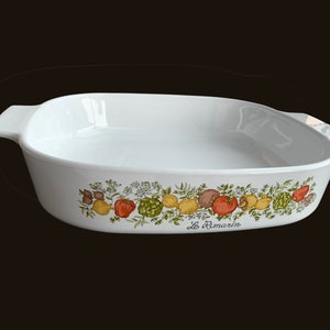 May include: White ceramic baking dish with a green and brown floral design featuring fruits and vegetables. The dish has two handles and the text "Le Remarin" is printed on the bottom.